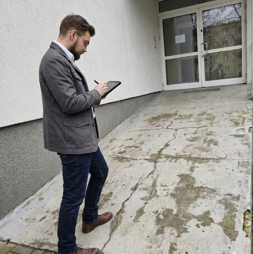 Audytor mierzący szerokość drzwi w budynku urzędu